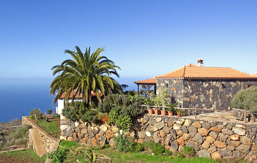 Casa rural en La Palma totalmente renovada, con interiores que combinan elementos de madera, colores cálidos y una agradable zona al aire libre con refrescantes palmeras
