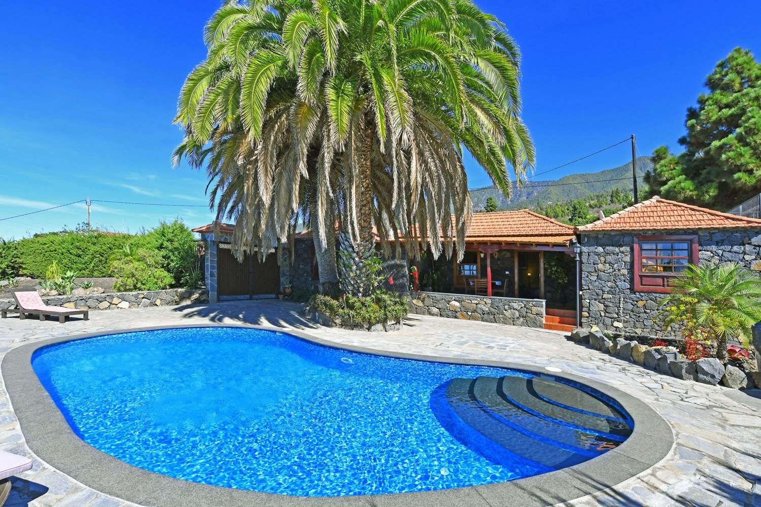 Belle maison de deux chambres à l'architecture originale en pierre des Canaries avec un magnifique jardin avec de majestueux palmiers et une piscine privée